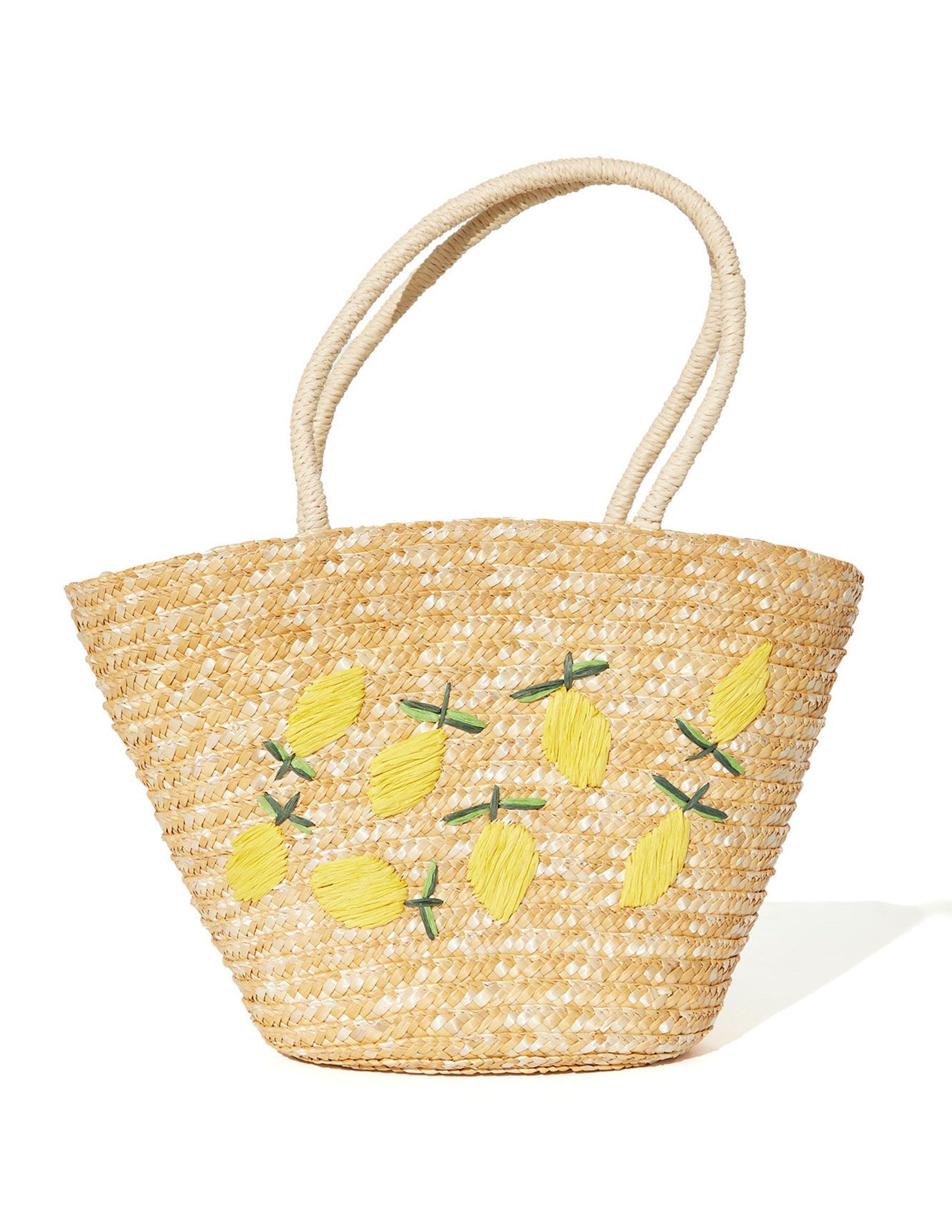 Bolso tipo tote de rafia beige con bordado de limones y asas trenzadas.