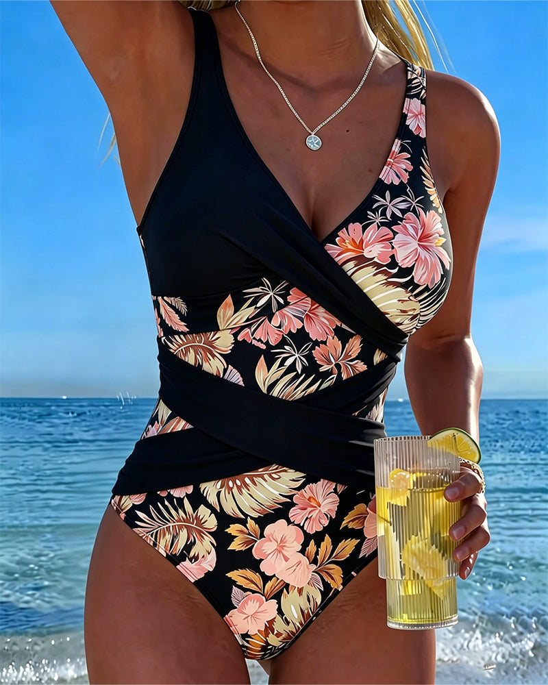 Traje de baño negro de una pieza, sin mangas, escote cruzado y estampado floral rosa.
