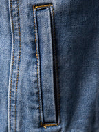 Detalle de chaqueta de mezclilla oscura: ojal rectangular en el panel delantero