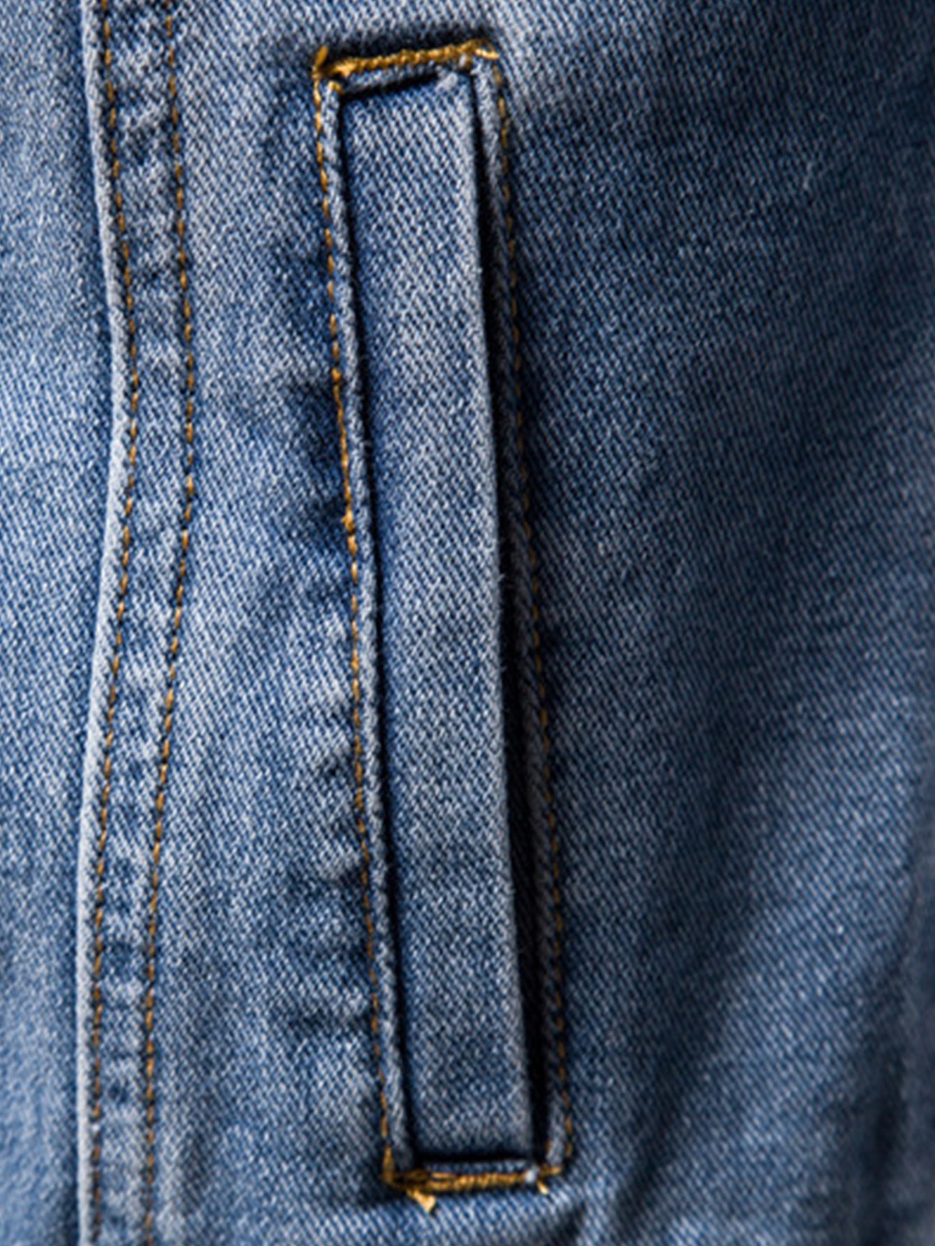 Detalle de chaqueta de mezclilla oscura: ojal rectangular en el panel delantero