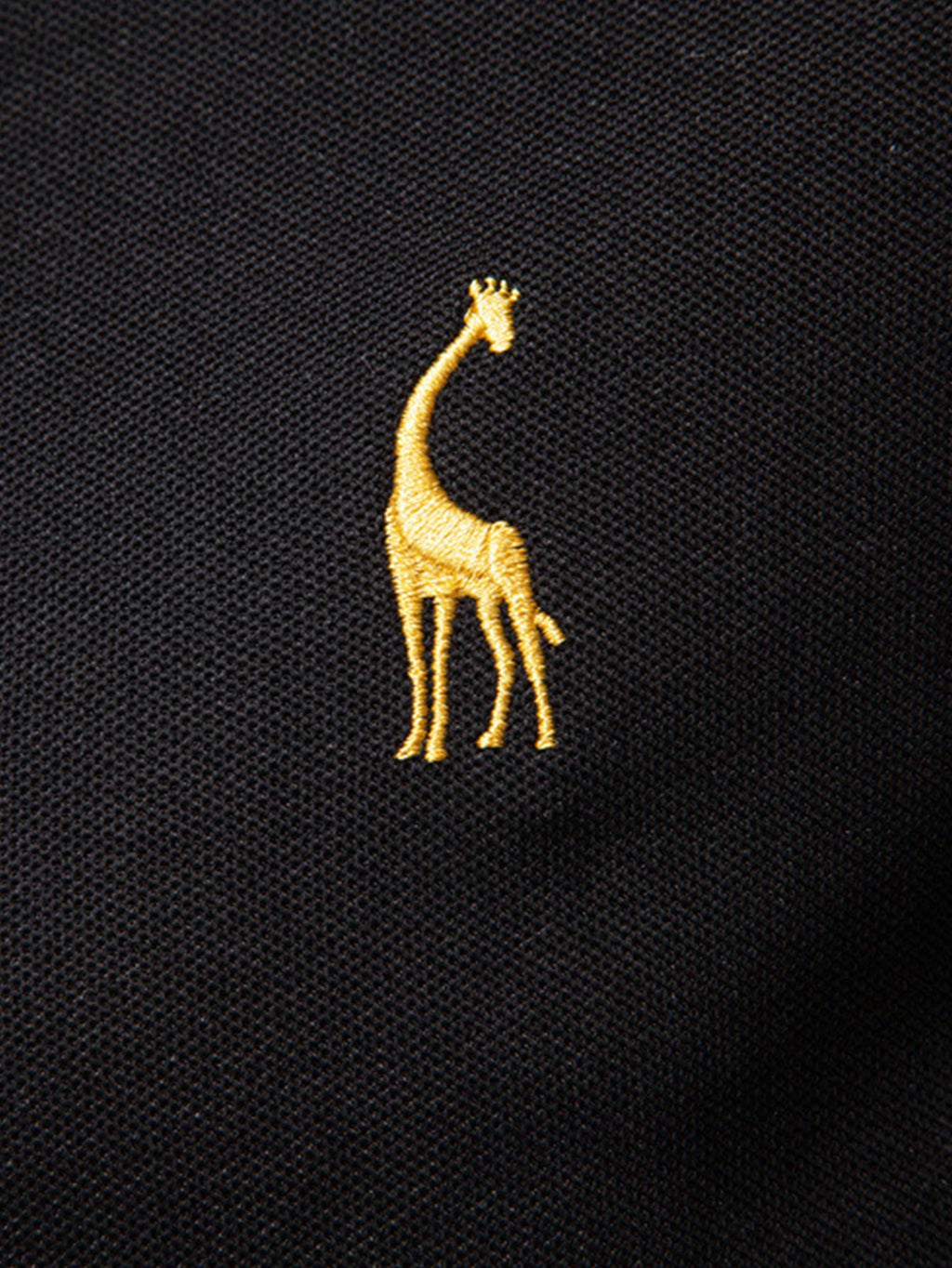 Polo negro con bordado de jirafa amarilla en el pecho.