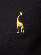 Polo negro con bordado de jirafa amarilla en el pecho.