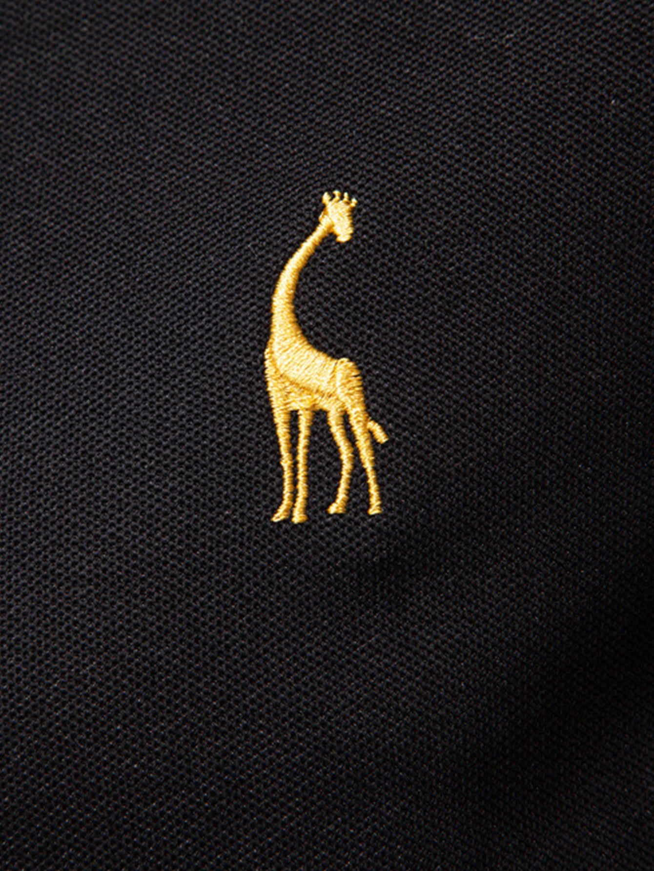 Polo negro con bordado de jirafa amarilla en el pecho.
