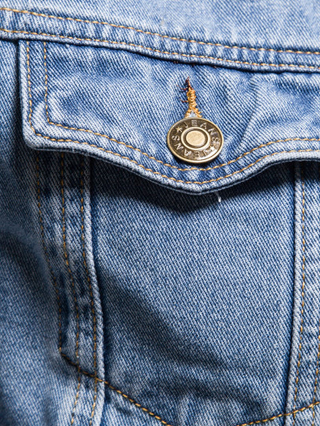 Detalle de chaqueta de mezclilla azul claro: parche con botón y costuras visibles