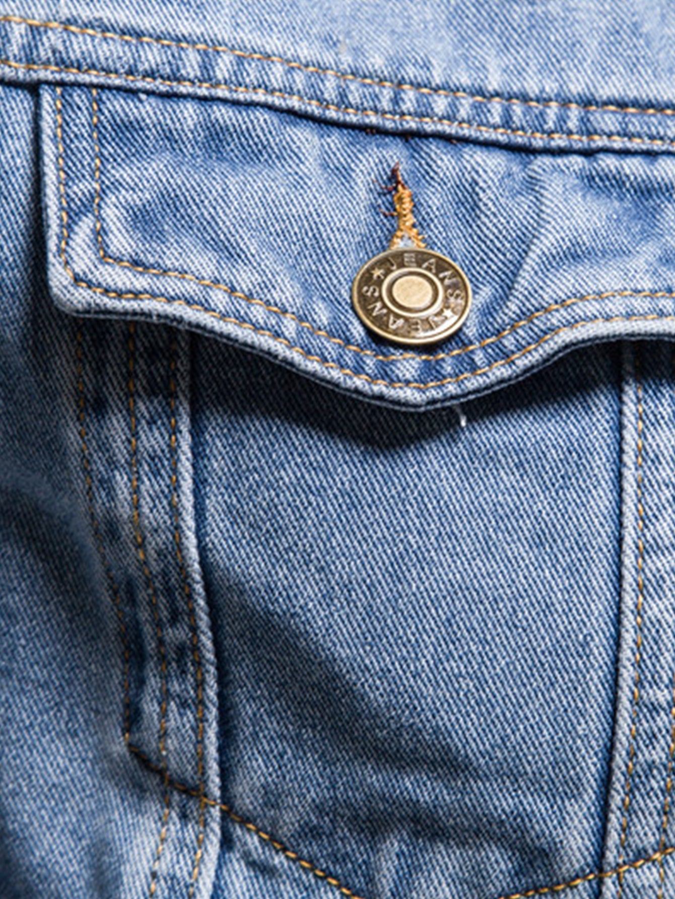 Detalle de chaqueta de mezclilla azul claro: parche con botón y costuras visibles
