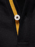 Polo negro con tapeta rayada amarilla y botón blanco en el cuello.