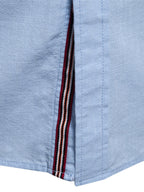 Camisa azul clara: detalle de vivo con rayas rojo, blanco y azul en la costura