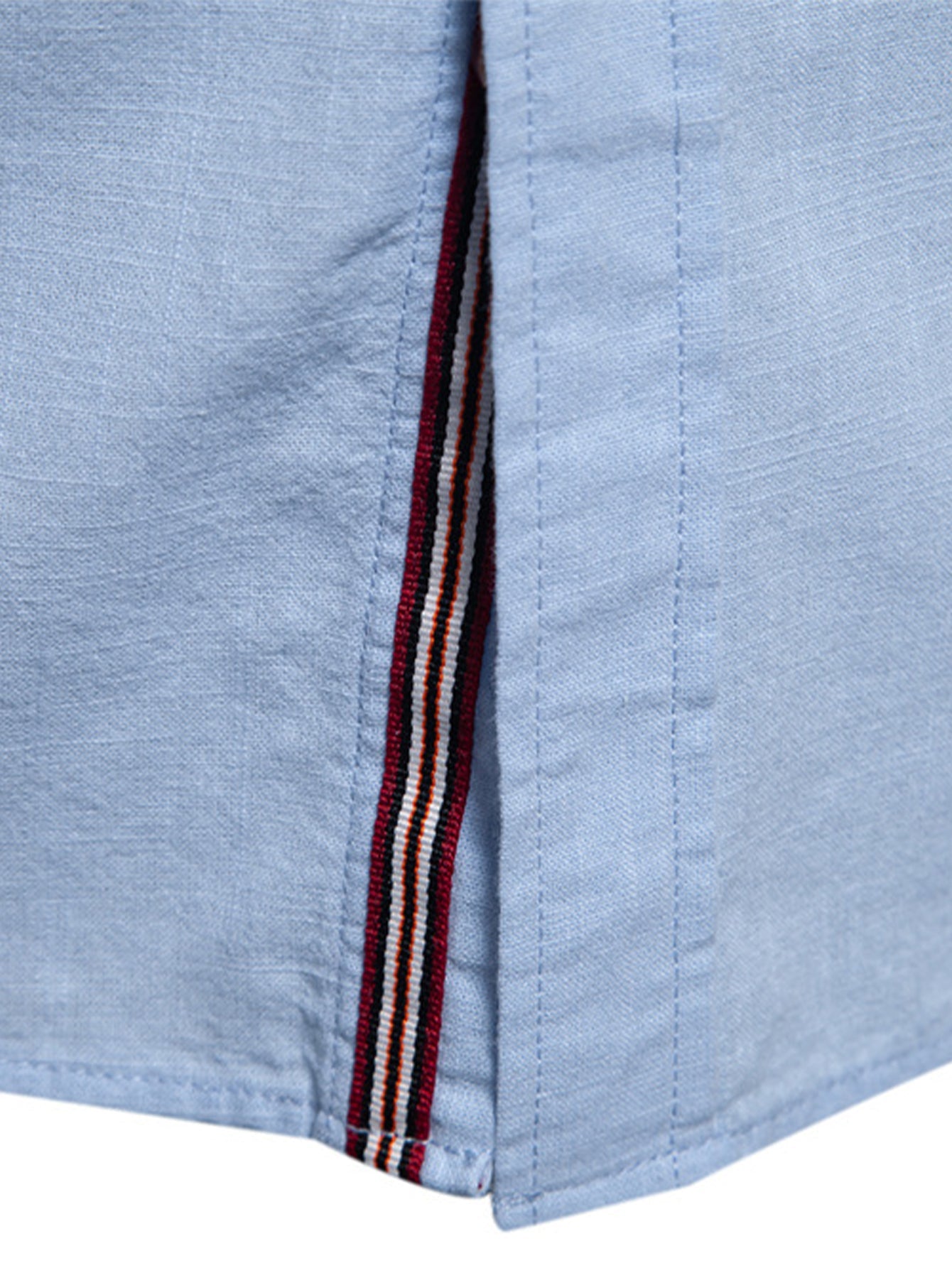 Camisa azul clara: detalle de vivo con rayas rojo, blanco y azul en la costura