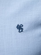 Camisa Ravello azul claro: detalle de bordado pequeño en el pecho y textura de tela