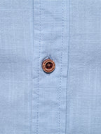 Camisa azul clara con botones y costuras visibles en el canesú