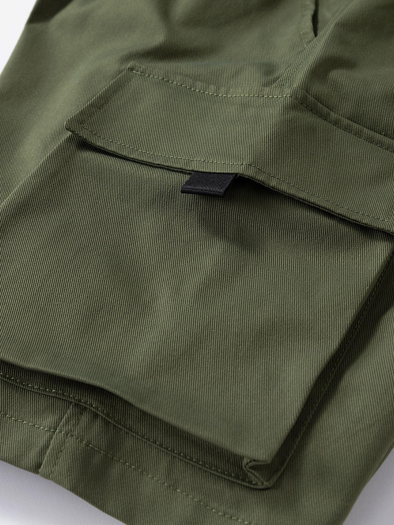 Pantalón corto verde oscuro con solapa de bolsillo y pespuntes visibles