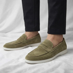 Mocasín de hombre de ante verde oliva, con tira cruzada y suela blanca.