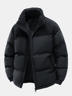 Chaqueta acolchada negra con capucha y cremallera; diseño liso con acolchado voluminoso.