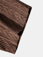Camisa café: vista de manga y dobladillo, tejido acanalado con textura marcada.