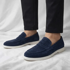 Mocasín de hombre de ante azul marino, con tira cruzada y suela blanca.
