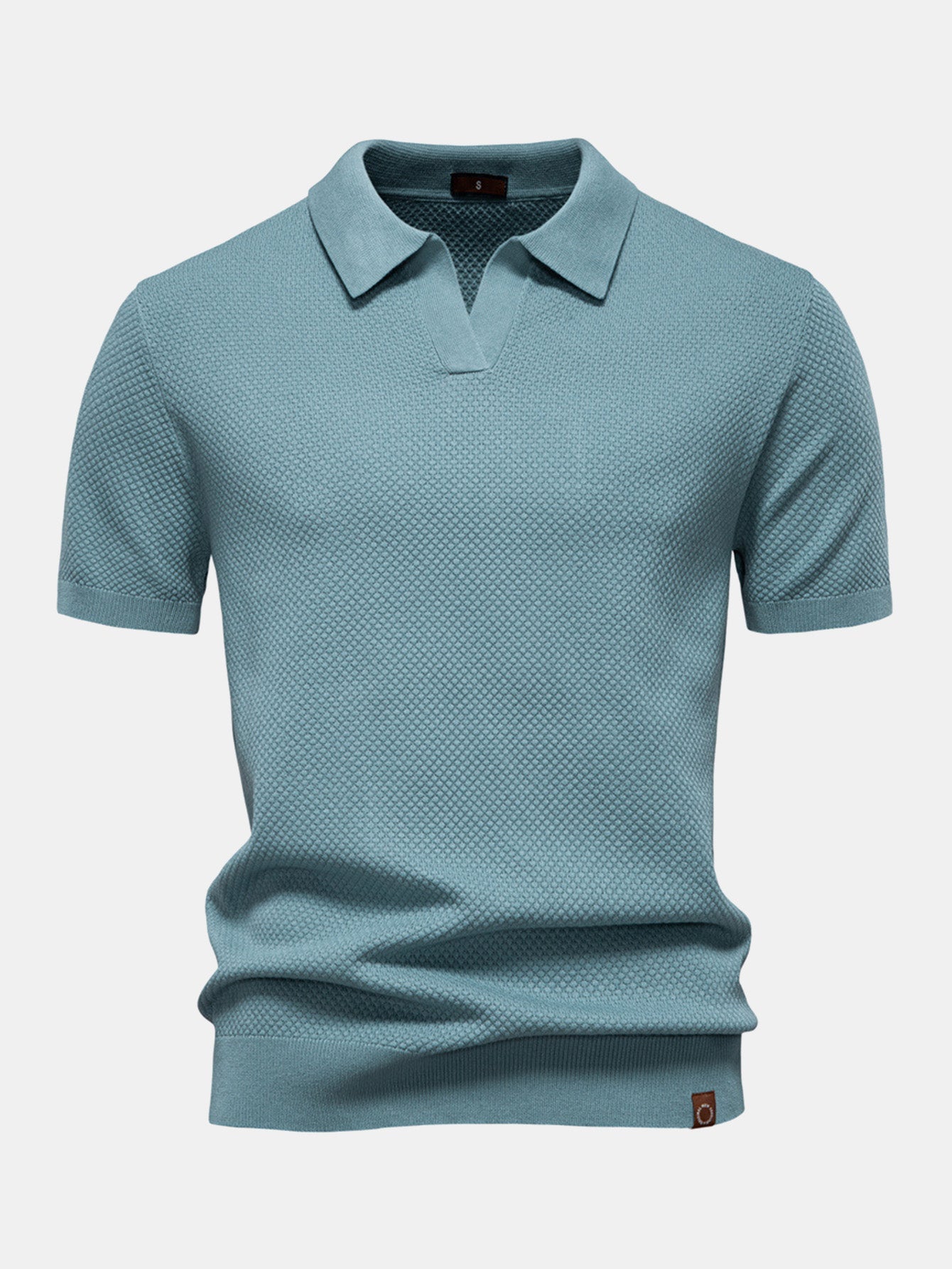 Polo de manga corta color cian, cuello camisero y pliegue en el bajo.