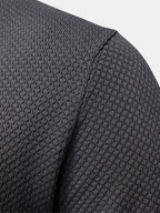 Polo gris oscuro: primer plano del hombro y manga con costura lateral visible