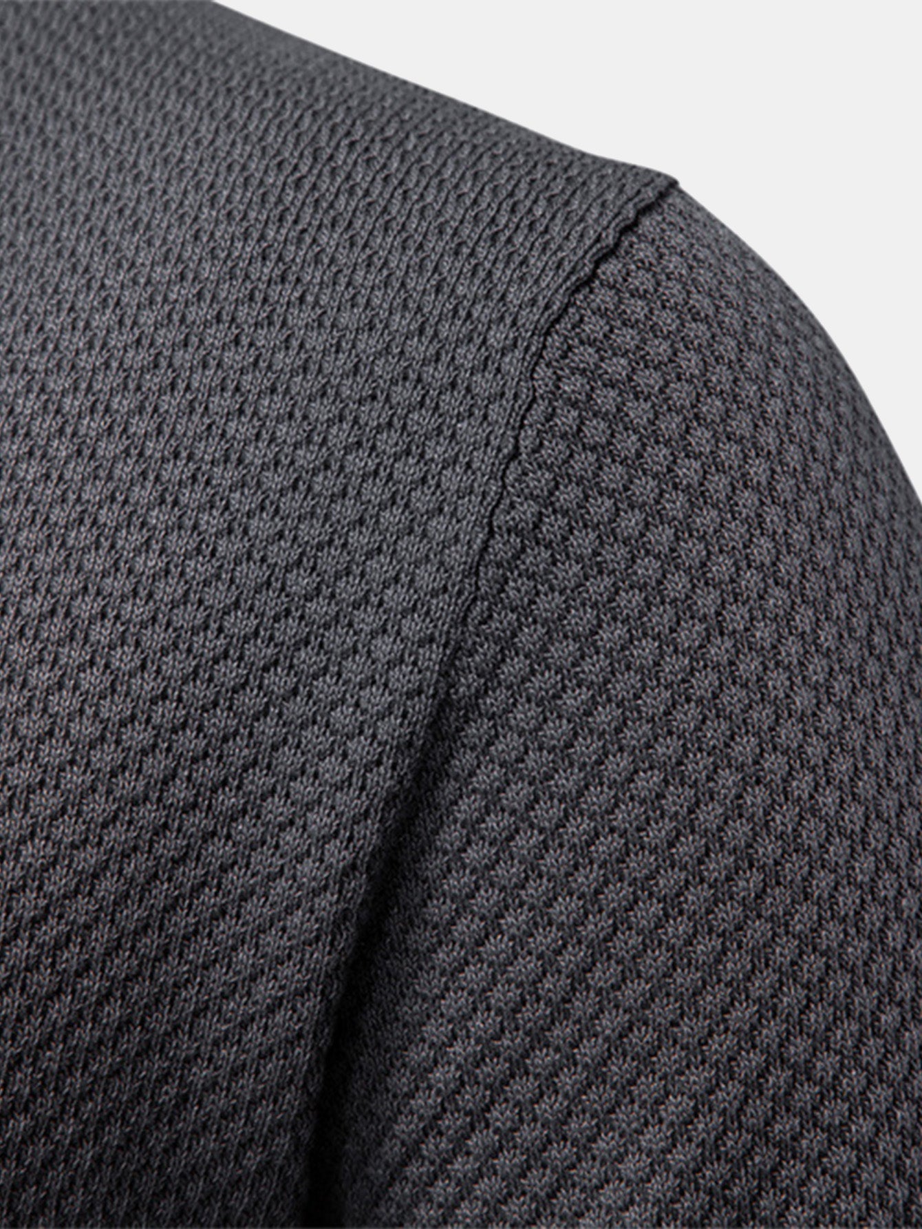 Polo gris oscuro: primer plano del hombro y manga con costura lateral visible
