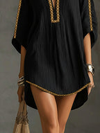 Vestido corto negro con dobladillo ondulado y ribete dorado, escote en V