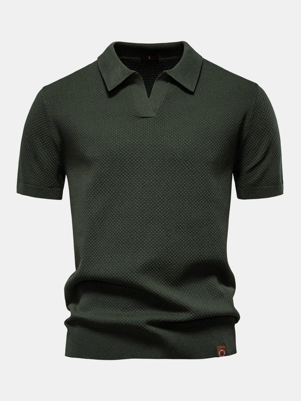 Polo de manga corta color verde oscuro, cuello camisero y etiqueta en el bajo.