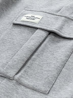 Etiqueta cosida en pantalón cargo gris claro, con costuras de bolsillo