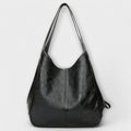 Bolso de piel negro estilo hobo con asas largas y placa en el frente