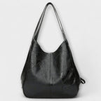 Bolso de piel negro estilo hobo con asas largas y placa en el frente