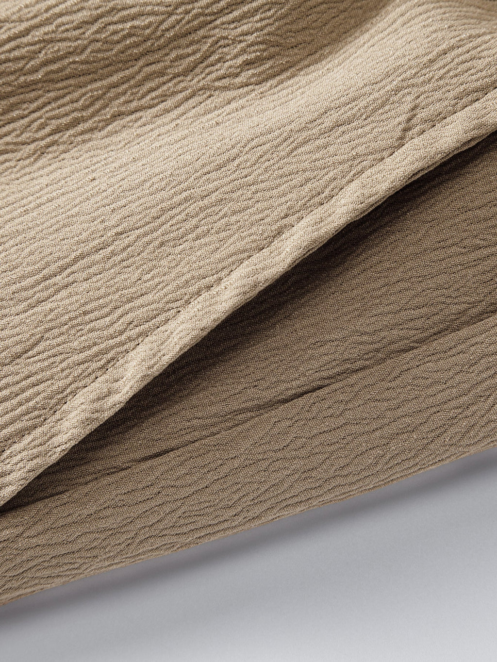 Pantalón corto beige de tela con textura y pliegues