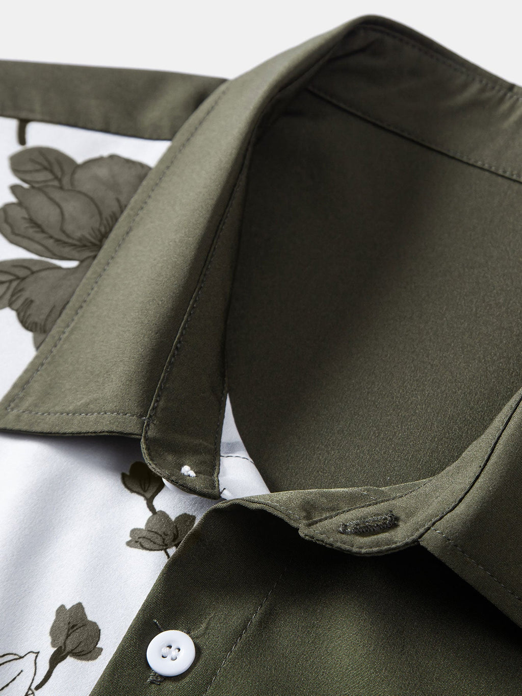 Detalle de botones blancos en camisa verde oscuro con panel blanco y estampado floral