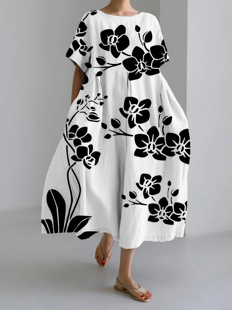 Vestido fluido blanco con estampado floral negro, manga corta y cuello redondo.