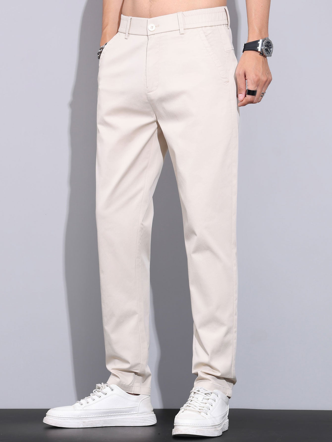 Pantalón recto de color beige, tiro medio, cierre con botón y bolsillos laterales