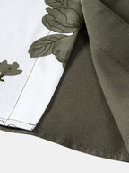 Borde de camisa verde oscuro con costura y estampado floral sobre fondo blanco