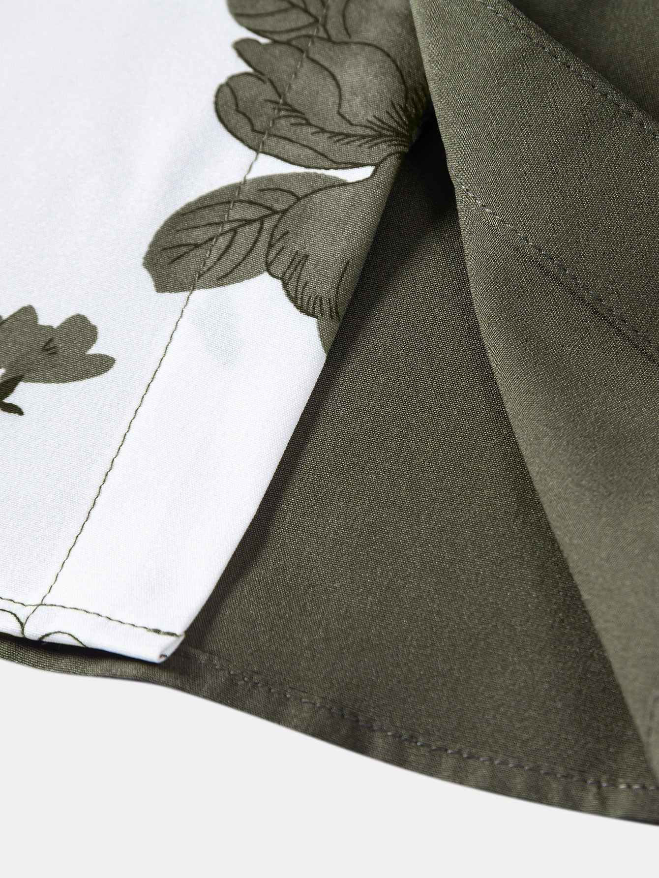 Borde de camisa verde oscuro con costura y estampado floral sobre fondo blanco