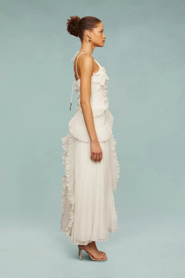 Vestido midi blanco con volantes en capas y abertura lateral, corte asimétrico.