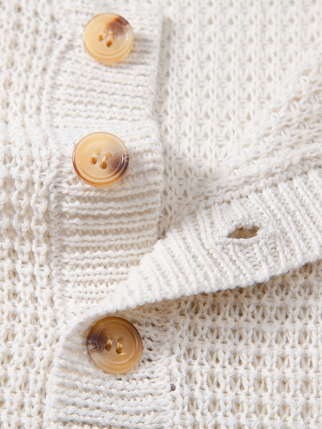Polo sin mangas crema: detalle de botones y tejido de punto