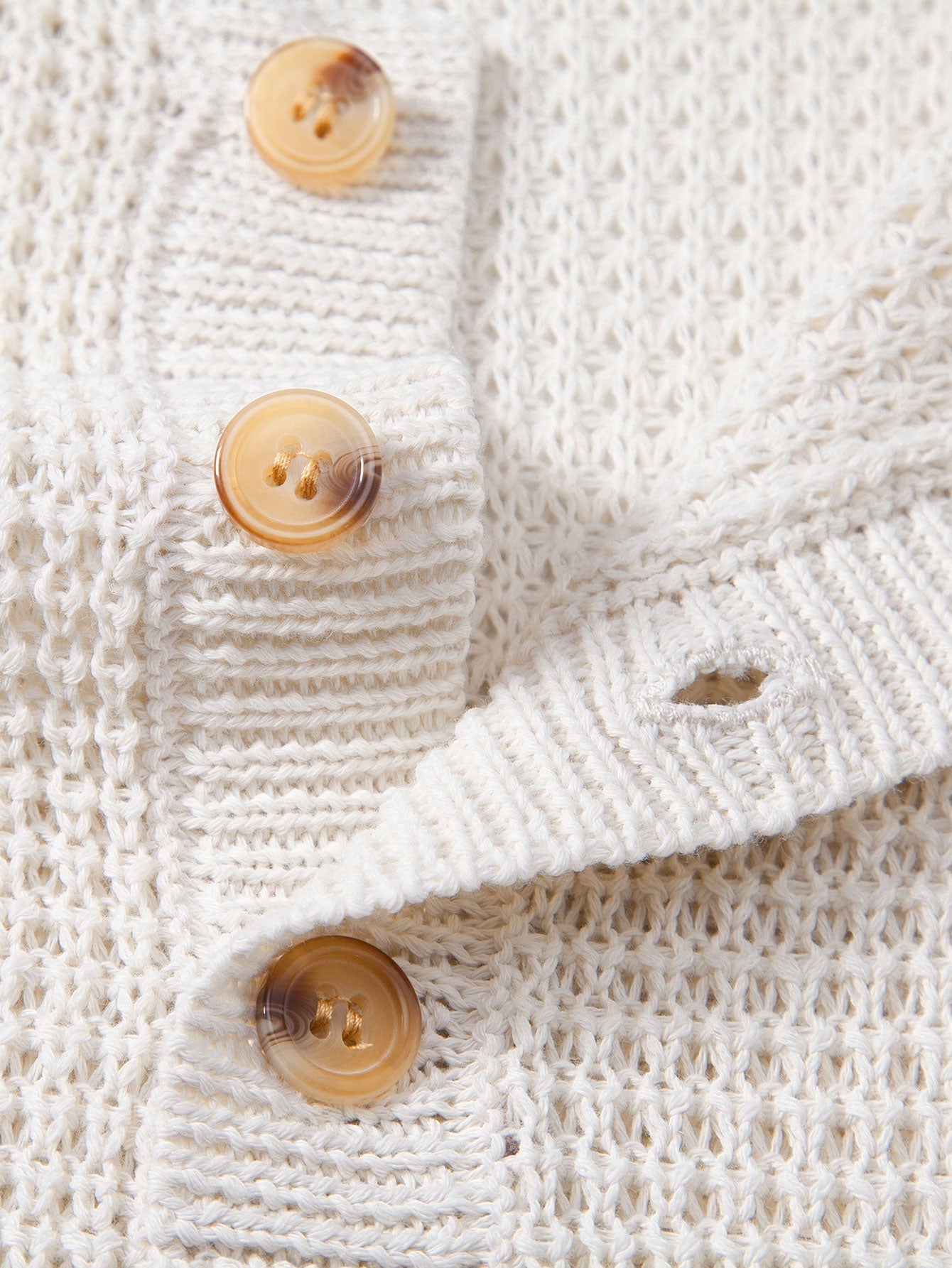 Polo sin mangas crema: detalle de botones y tejido de punto