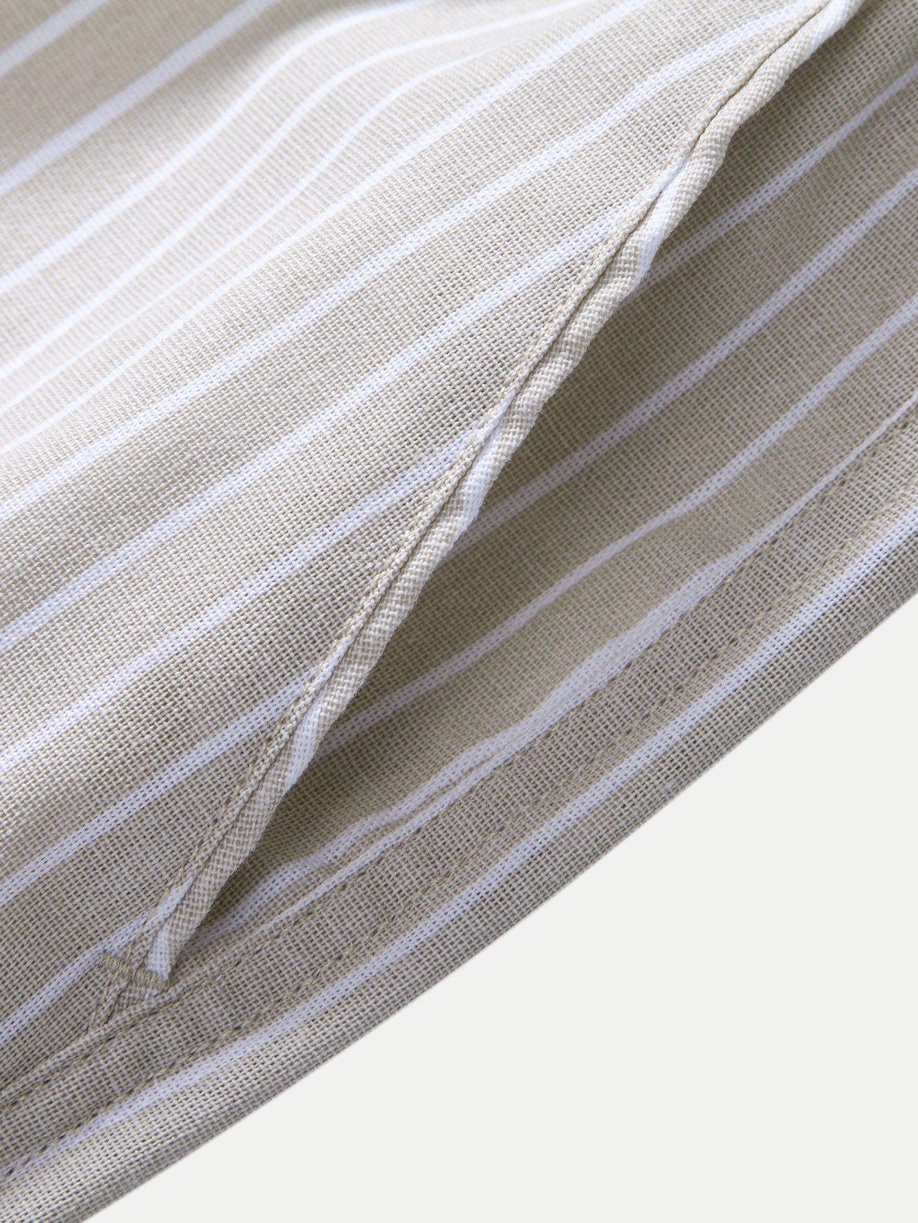 Detalle de tela del pantalón de lino a rayas beige, pliegues y costura