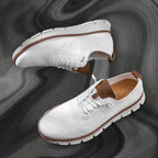 Zapatilla deportiva blanca tejida con cordones, borde marrón y suela blanca