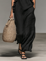 Vestido largo de lino negro con caída amplia y volantes en el escote, sin mangas.