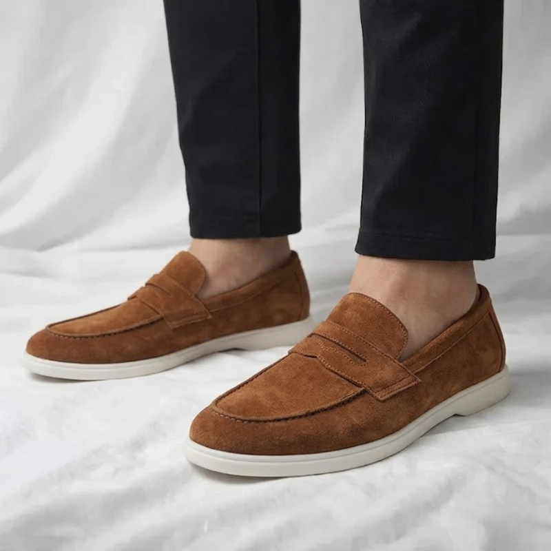 Mocasín de hombre de ante color camel, con tira cruzada y suela blanca.