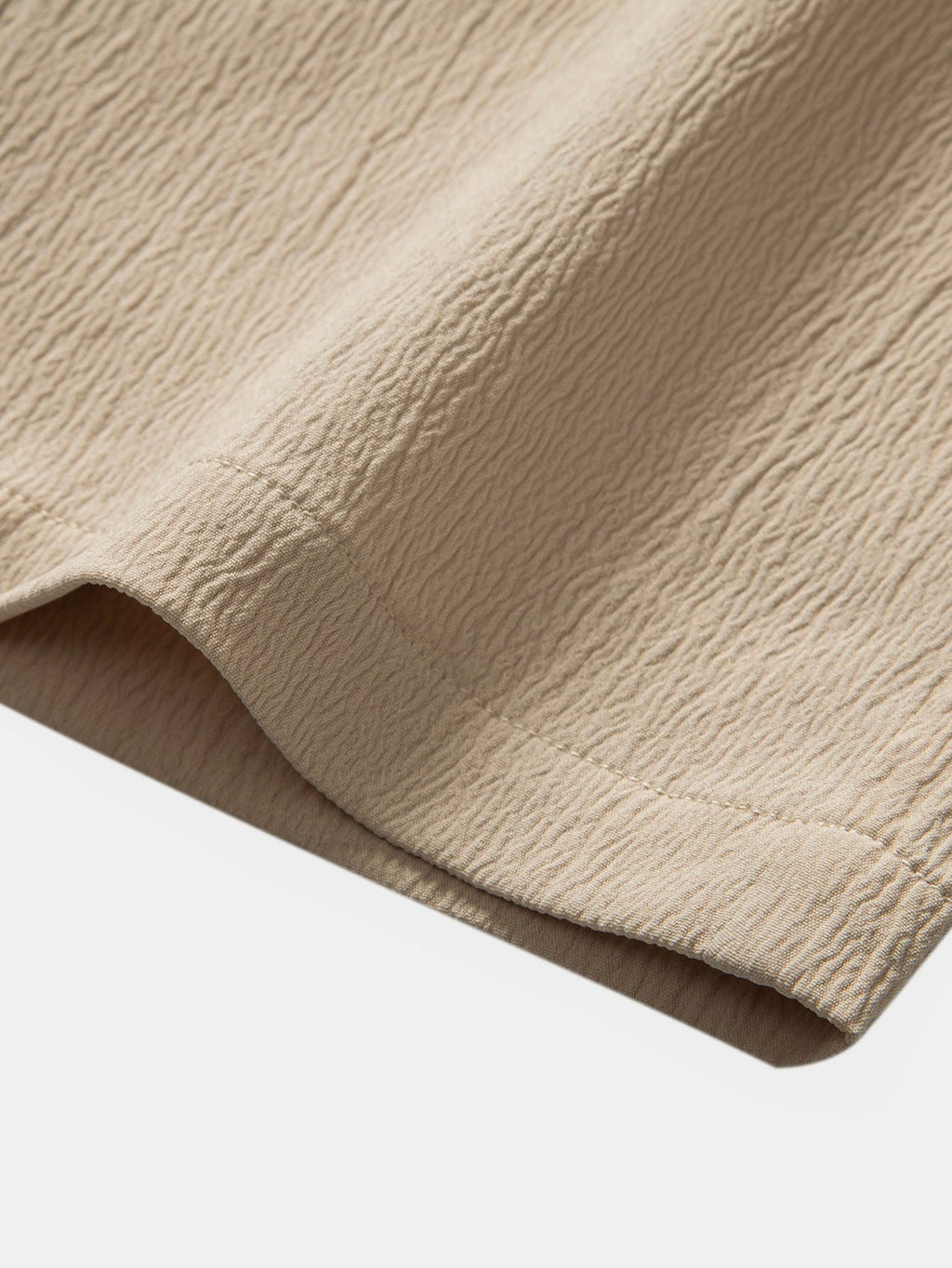 Borde inferior del pantalón con tela texturizada beige y dobladillo elástico.