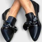 Mocasines negros tipo loafer con lazo frontal y textura efecto cocodrilo