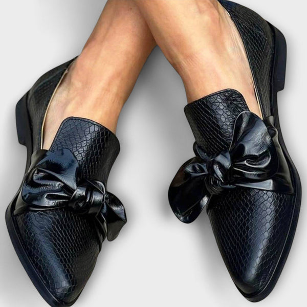 Mocasines negros tipo loafer con lazo frontal y textura efecto cocodrilo