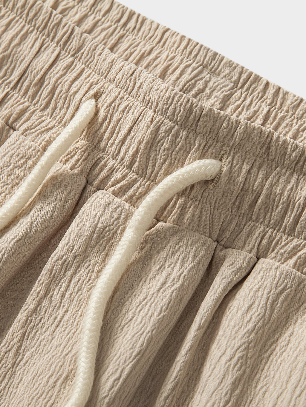 Tela del pantalón texturizada color beige, detalle de la cintura con cordón.
