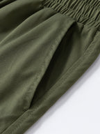 Pantalón corto verde oscuro de tela: costuras visibles en la pierna y dobladillo.