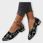 Bailarinas Amélie negras con estampado dorado y tacón ancho bajo; con pulsera de tobillo
