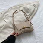 Bolso mini beige con solapa, hebilla dorada y asas trenzadas ajustables.