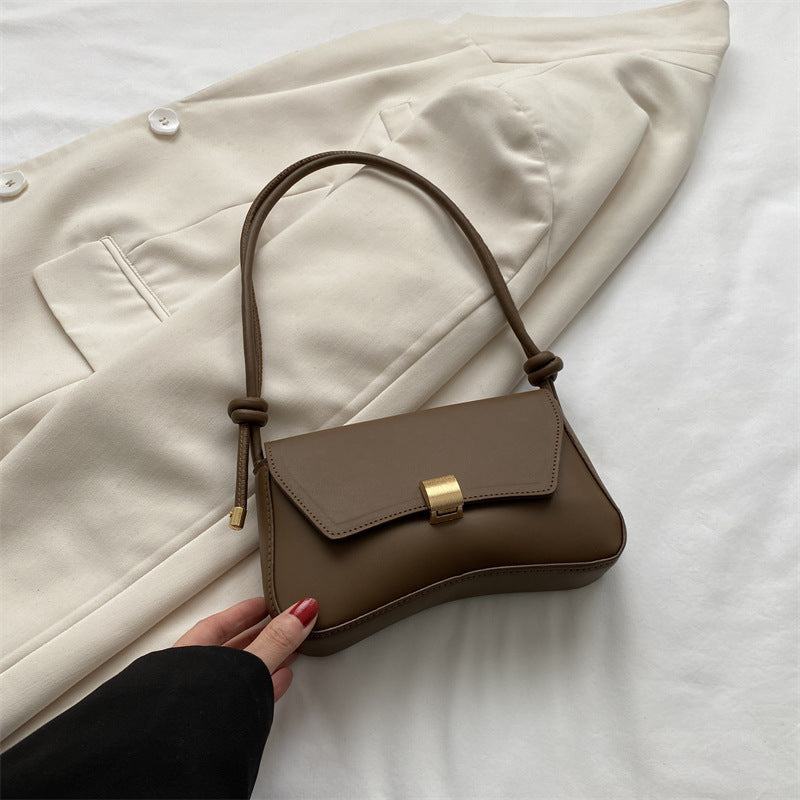 Bolso mini marrón con solapa y hebilla dorada, asas trenzadas y tira corta.