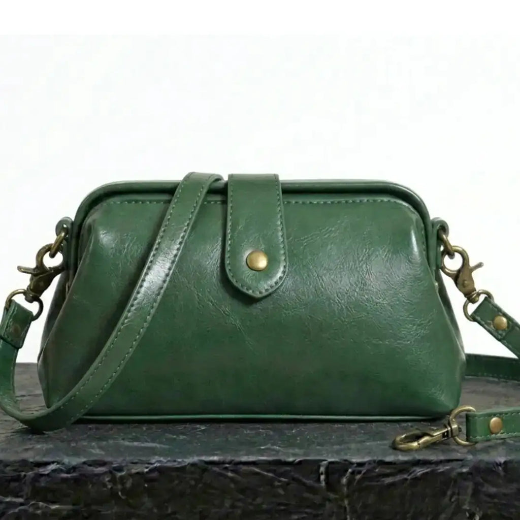 Bolso bandolera vintage de cuero verde con correa cruzada y hebilla dorada.