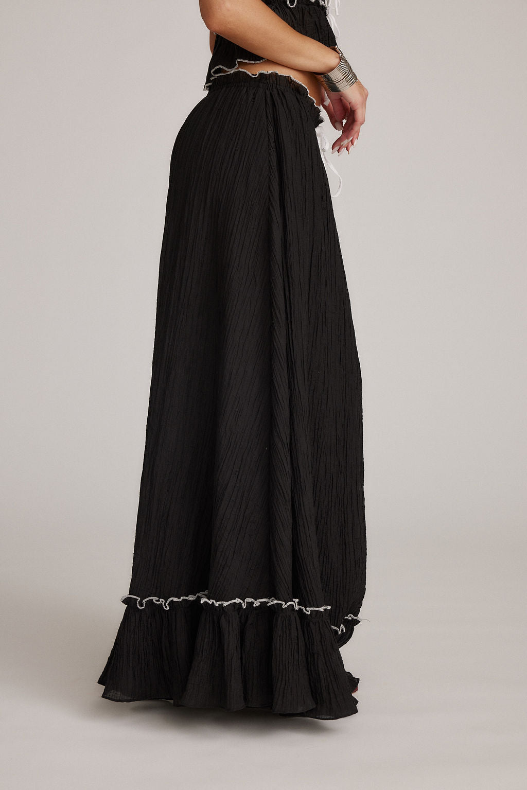 Falda maxi negra con textura plisada y volante inferior con ribete claro